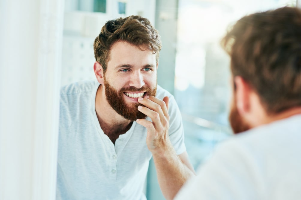 man viewing teeth in mirror